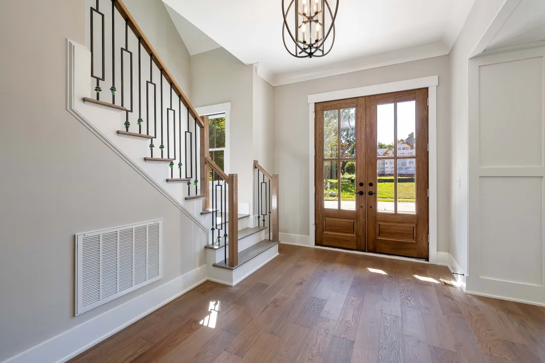 Bright foyer with a floating staircase and wire chandelier