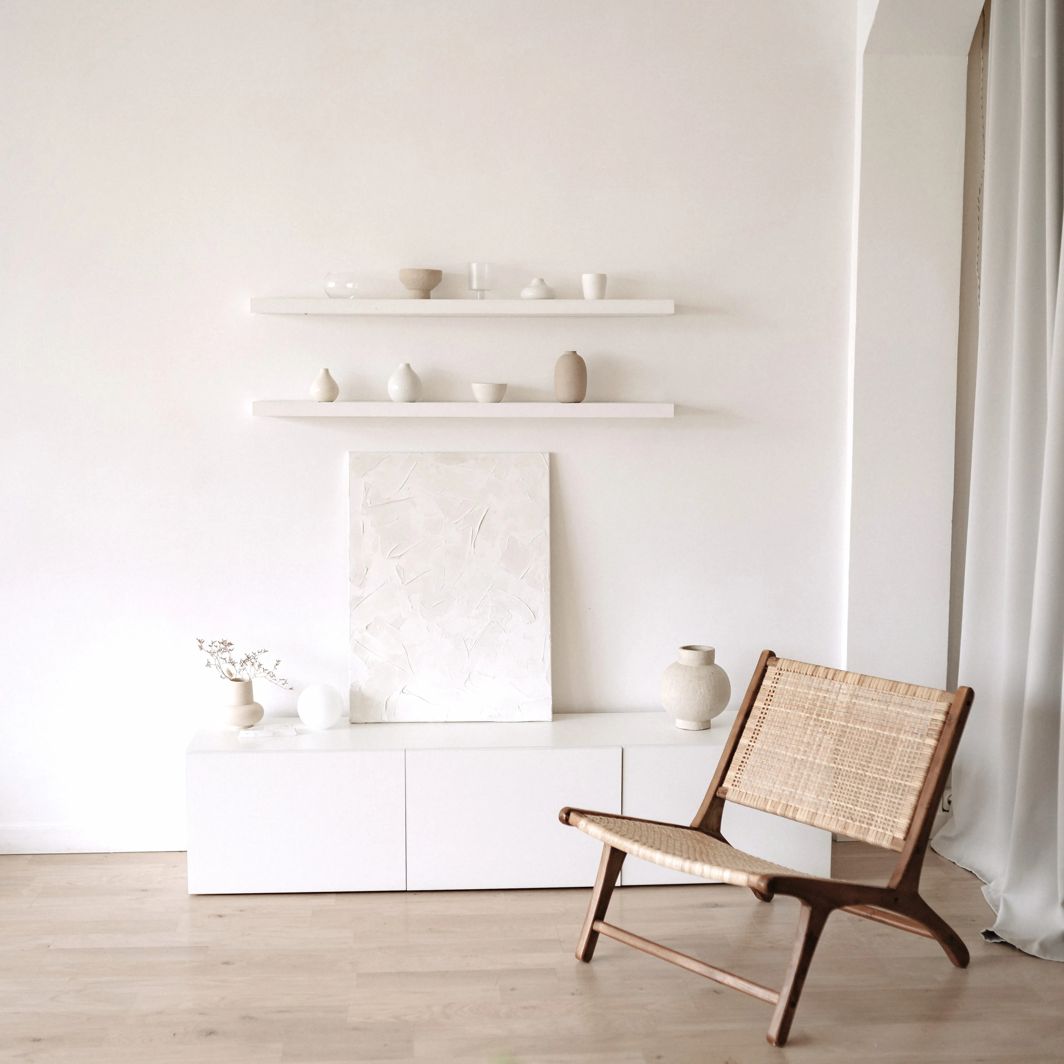 Serene Japandi interior — low white console, neutral ceramics, and a wishbone chair by sheer curtains
